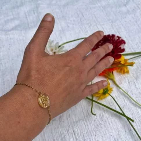 Bracelet en acier inoxydable doré avec inclusion de fleurs de sureau inclu dans de la résine transparente porté - bijou fleur