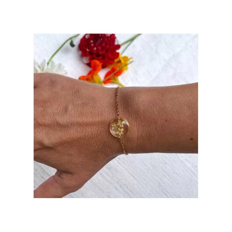 Bracelet en acier inoxydable doré avec inclusion de fleurs de sureau inclu dans de la résine transparente porté - bijou fleur