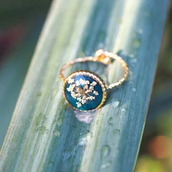 Bague en acier inoxydable doré en fleurs de carotte sauvage sur un fond émeraude - bijou fleur Clermont