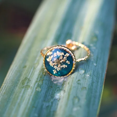 Bague en acier inoxydable doré en fleurs de carotte sauvage sur un fond émeraude - bijoux en fleurs Clermont