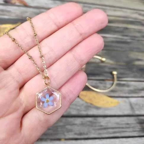 Collier hexagone doré avec inclusion de fleur de myosotis bleues