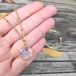 Collier hexagone doré avec inclusion de fleur de myosotis bleues