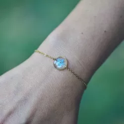 Bracelet doré avec inclusion de fleur de myosotis bleu porté au poignet - bijou fleur