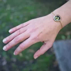 Bracelet rond en acier inoxydable doré avec inclusion de fleur de pensée dans de la résine transparente porté - bijou fleur