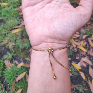 dos de bracelet doré avec inclusion de fleurs de bleuet porté sur un poignet