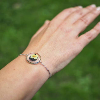 Bracelet rond en acier inoxydable argenté avec inclusion de fleur de pensée dans de la résine transparente porté