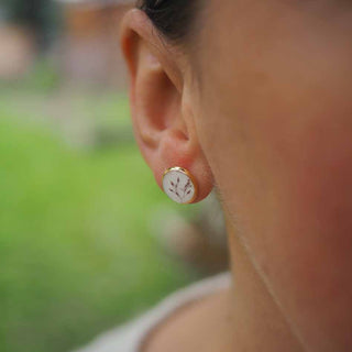 Puces en acier inoxydable doré avec inclusion de fleurs de poacée inclu dans de la résine de couleur blanche portée à l'oreille
