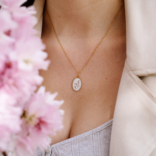 Bijou vraie fleur clermont - Collier doré avec de la poacée sur fond blanc.