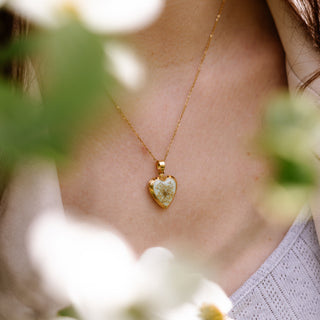 Bijou en fleurs séchées - Collier médaillon en forme de coeur en fleurs de carotte sauvage sur fond vert pale porté 1