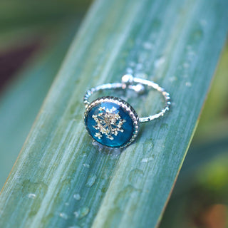 Bague en acier inoxydable argentée en fleurs de carotte sauvage sur un fond émeraude - bijou fleuri clermont