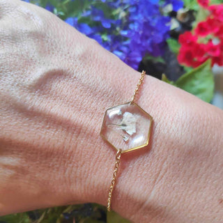 Bracelet hexagone en acier inoxydable doré avec inclusion de fleurs de gypsophile porté au poignet - bijou fleur