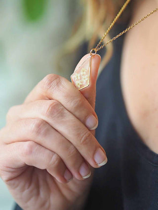 Collier losange en acier inoxydable doré avec inclusion de fleurs de sureau inclu dans de la résine transparente porté