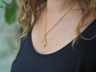 Collier losange en acier inoxydable doré avec inclusion de fleurs de sureau inclu dans de la résine transparente porté