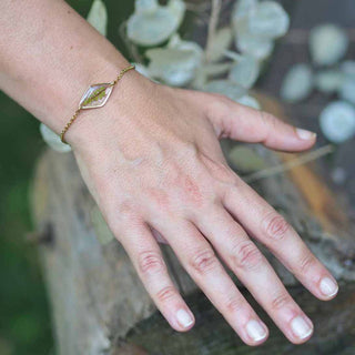 Bracelet en laiton doré à l'or fin avec inclusion de feuille de fougère verte porté au poignet - bijou fleur