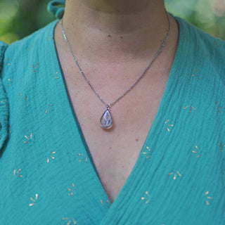 Collier en acier inoxydable argenté avec inclusion de fleurs de bleuet porté autour du cou - collier fleur