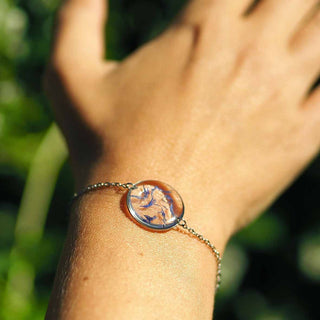 bracelet argenté avec inclusion de fleurs de bleuet porté sur un poignet - bijou fleur