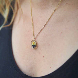 Collier en acier inoxydable doré avec inclusion de fleur de pensée dans de la résine transparente porté