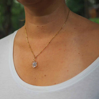 Collier hexagone doré avec inclusion de fleur de myosotis bleues porté - collier fleur