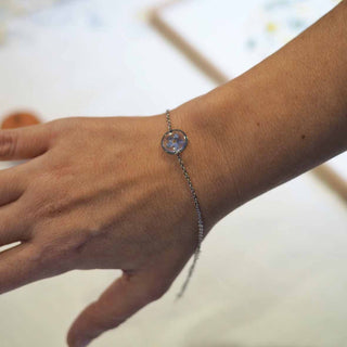 Bracelet argenté avec inclusion de fleur de myosotis bleu porté au poignet
