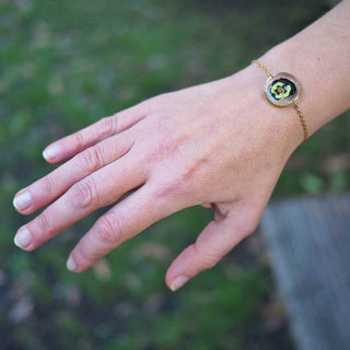 Bracelet rond en acier inoxydable doré avec inclusion de fleur de pensée dans de la résine transparente porté - bijou fleur