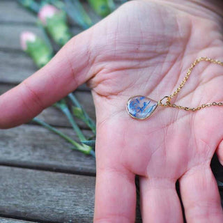 Collier en laiton doré à l'or fin avec fleurs de bleuet posé sur une main - collier fleur - Bijoux en vraies fleurs Clermont