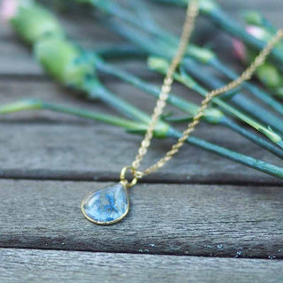 Collier en laiton doré à l'or fin avec fleurs de bleuet posé sur une main - collier fleur - Bijoux vraies fleurs à Clermont