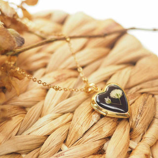 Médaillon doré en forme de coeur avec inclusion d'une fleur de gypsophile blanche dans de la résine noire - collier fleur