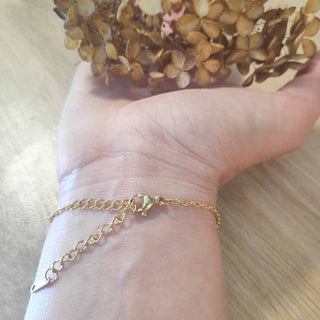 Bracelet rond en acier inoxydable doré avec inclusion de fleur de carotte sauvage dans de la résine transparente au poignet