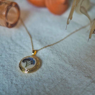 Médaillon Myosotis en acier inoxydable doré avec fleurs de myosotis bleues sur fond blanc - collier fleur Clermont