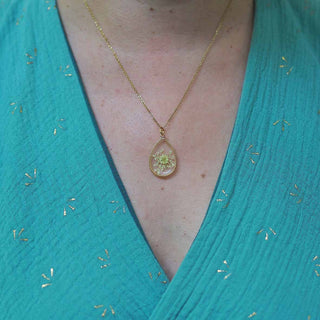 Collier en acier inoxydable doré avec inclusion de fleur de carotte dans de la résine transparente porté autour du cou